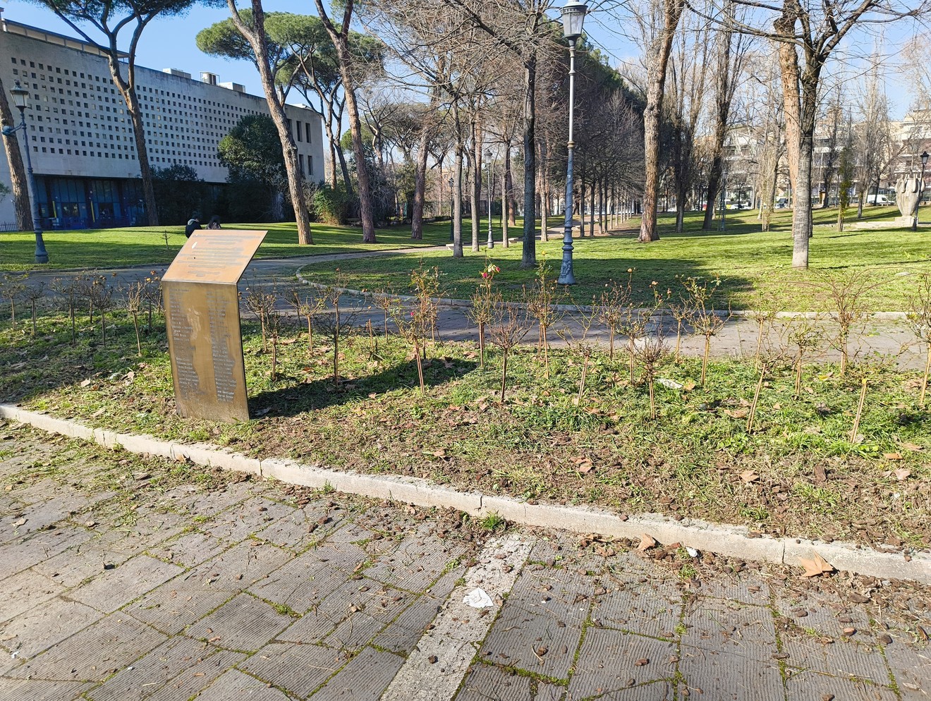 Monumento alle donne cadute in difesa di Roma immerso in un parco con alberi e vialetti.
