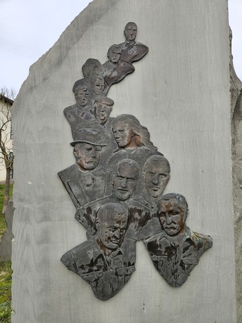 Monumento ai Partigiani con i ritratti di diversi volti scolpiti nella pietra.