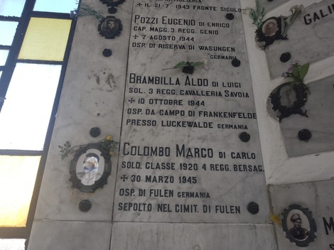 Lapidi commemorative di soldati caduti per la libertà, adornate con fiori e immagini.