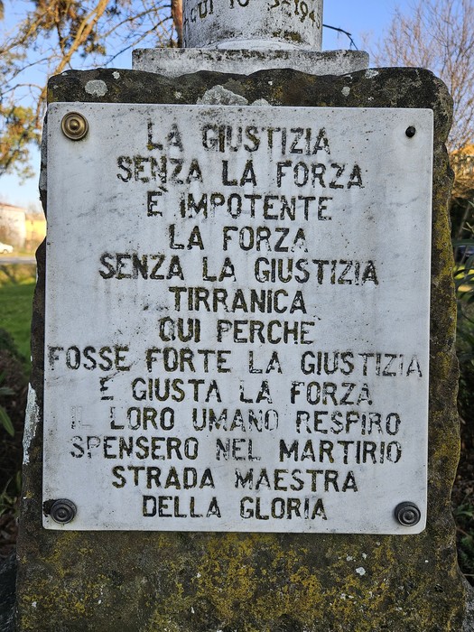 Cippo in pietra con iscrizioni dedicate a "Brambilla, Fava e Pezzali" in un contesto naturale.