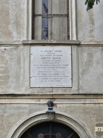 Lapide commemorativa dedicata a Bruno Fossi, affissa su una facciata di un edificio storico.