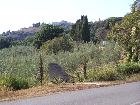 Cippo del Saracino: monumento situato tra alberi di ulivo in un paesaggio collinare sereno.