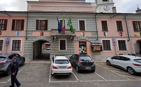 Municipio di Sozzi con bandiere e auto posteggiate in un'area comunale. Architettura storica e ambiente urbano.
