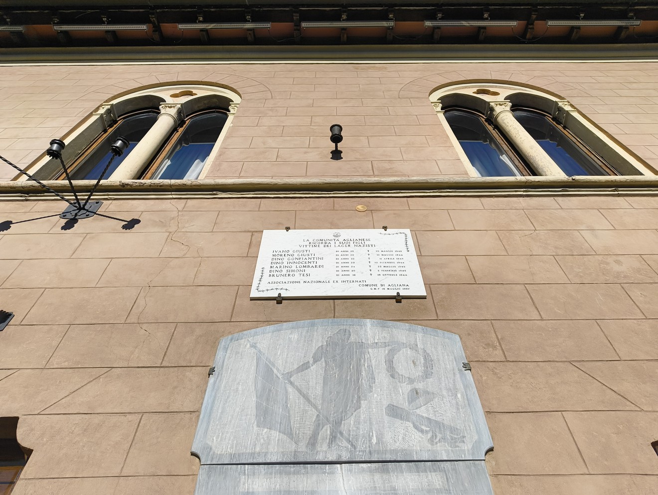 Lapide commemorativa dedicata ai deportati, posta su un edificio storico. Memoria e rispetto per le vittime.