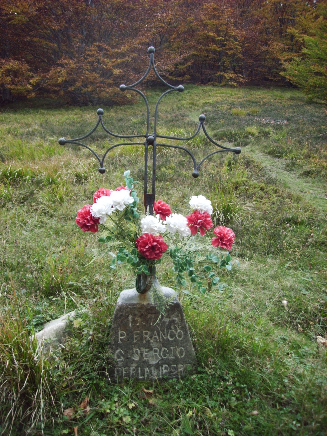 Cippo commemorativo decorato con fiori, immerso nella natura, in memoria di Giovannetti e Prioreschi.
