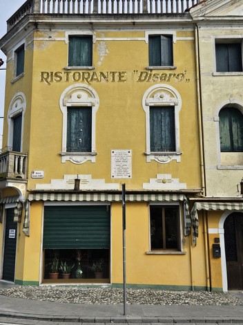 Lapide commemorativa in una facciata gialla, con riferimenti a Furlan ed Artico.