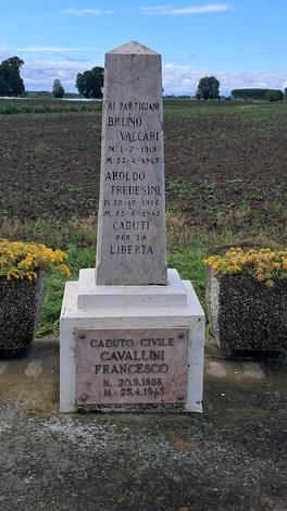 Cippo commemorativo dedicato ai partigiani Vaccari, Tredesini e al civile Cavallini, immerso in un paesaggio rurale.