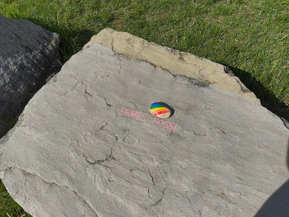 Monumento in memoria dei partigiani caduti, situato a Monte Sabbiuno, con roccia e decorazioni colorate.