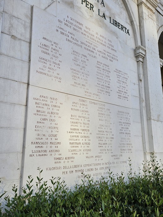 Lapide commemorativa in onore dei caduti per la libertà, con nomi incisi su una superficie di pietra.