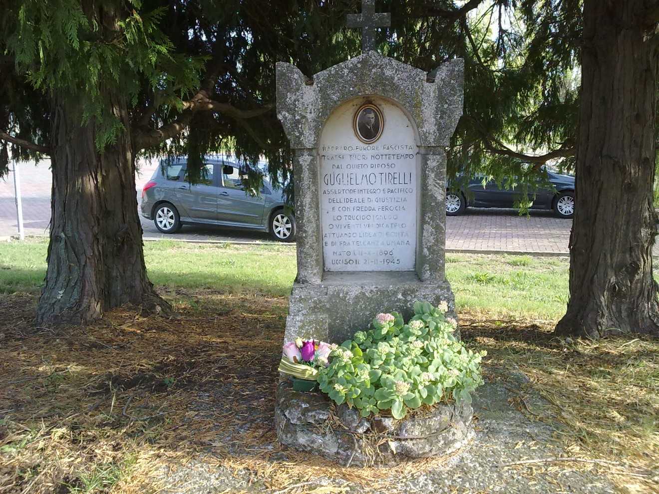 Monumento a Tirelli, dedicato alla memoria di un valoroso, circondato da alberi e fiori.