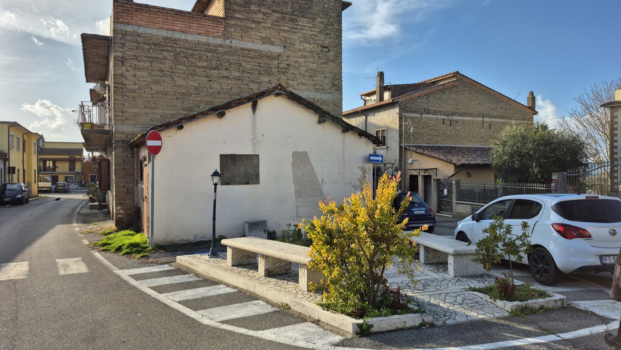 Monumento al Campo PG54 situato in una zona residenziale con panchine e vegetazione.
