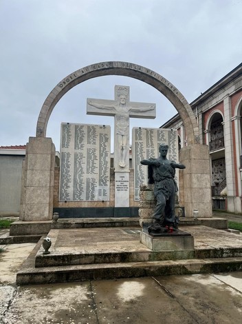 Monumento al "Campo della Gloria" con statue e nomi di caduti, in un'atmosfera solenne e commemorativa.