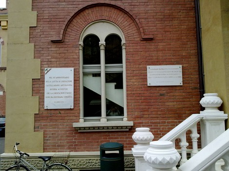 Lapidi commemorative dedicate alla Resistenza, affisse su un edificio di mattoni rossi.