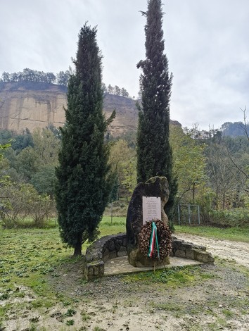 Monumento agli uccisi di Rio Conco, circondato da alberi e natura, in memoria dei caduti.