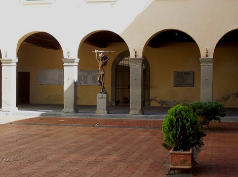 Lapide commemorativa di Ristori in un cortile, con statua al centro e archi decorativi sullo sfondo.