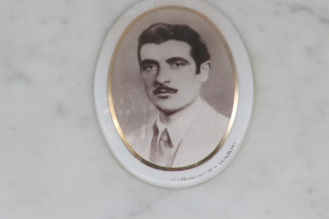 Ritratto in bianco e nero di un uomo con baffi, incorniciato su una targa commemorativa.