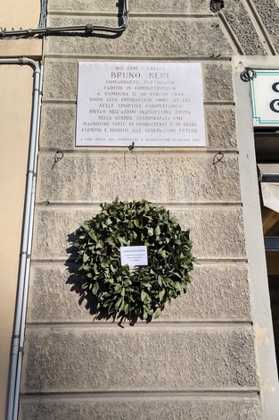 Lapide commemorativa a Bruno Neri, candidato partigiano, situata su un muro di un edificio.