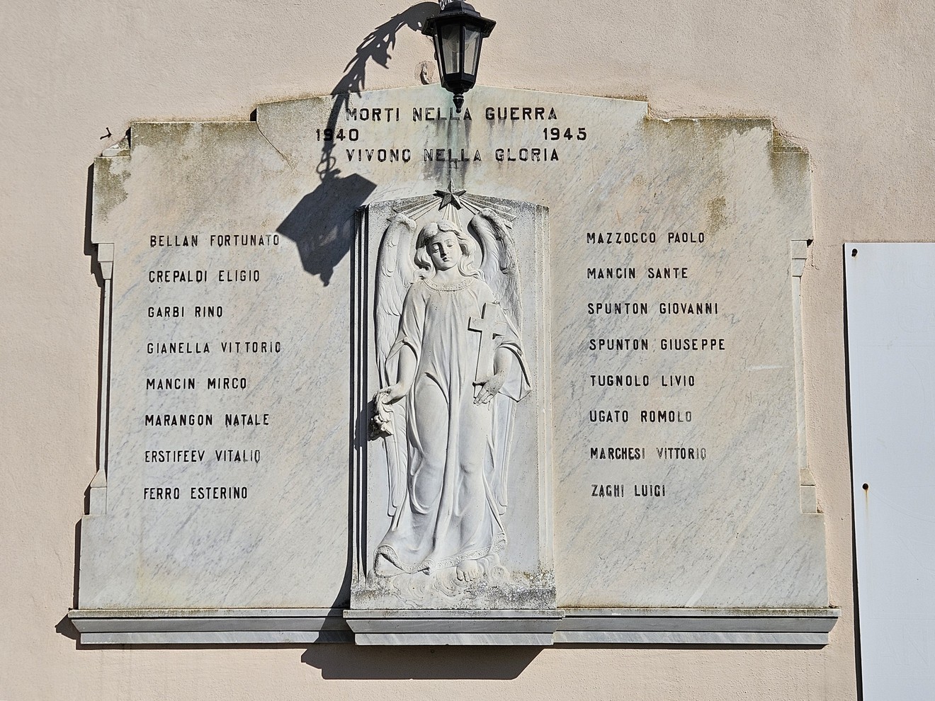 Lapide commemorativa dedicata ai caduti della guerra 1940-1945, con nomi incisi e un angelo in rilievo.