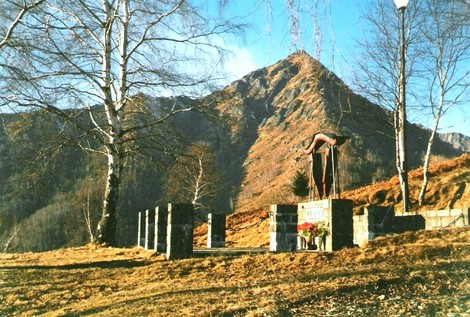 Memoriale dedicato ai partigiani, circondato da natura e montagne, simbolo di resistenza e libertà.
