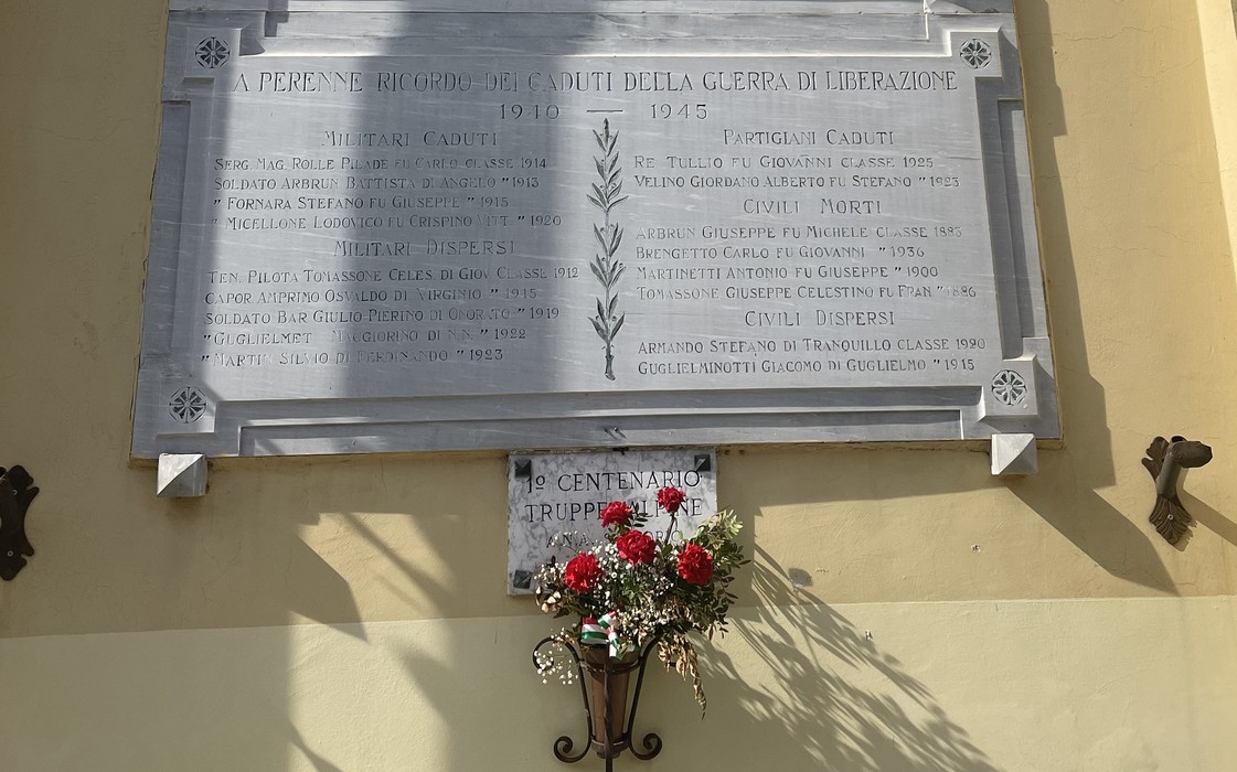 Lapide commemorativa dedicata ai caduti della guerra di liberazione, con fiori in omaggio.