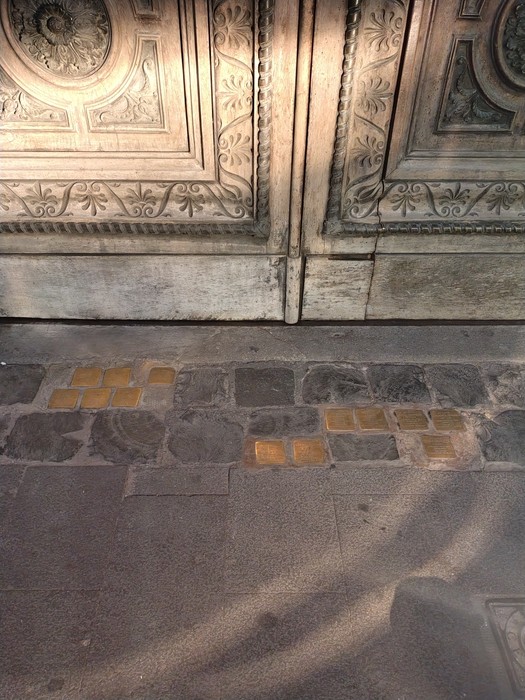 Pietre d'inciampo dedicate alle famiglie Piperno, Coen, Sonnino e Romanelli su un marciapiede.