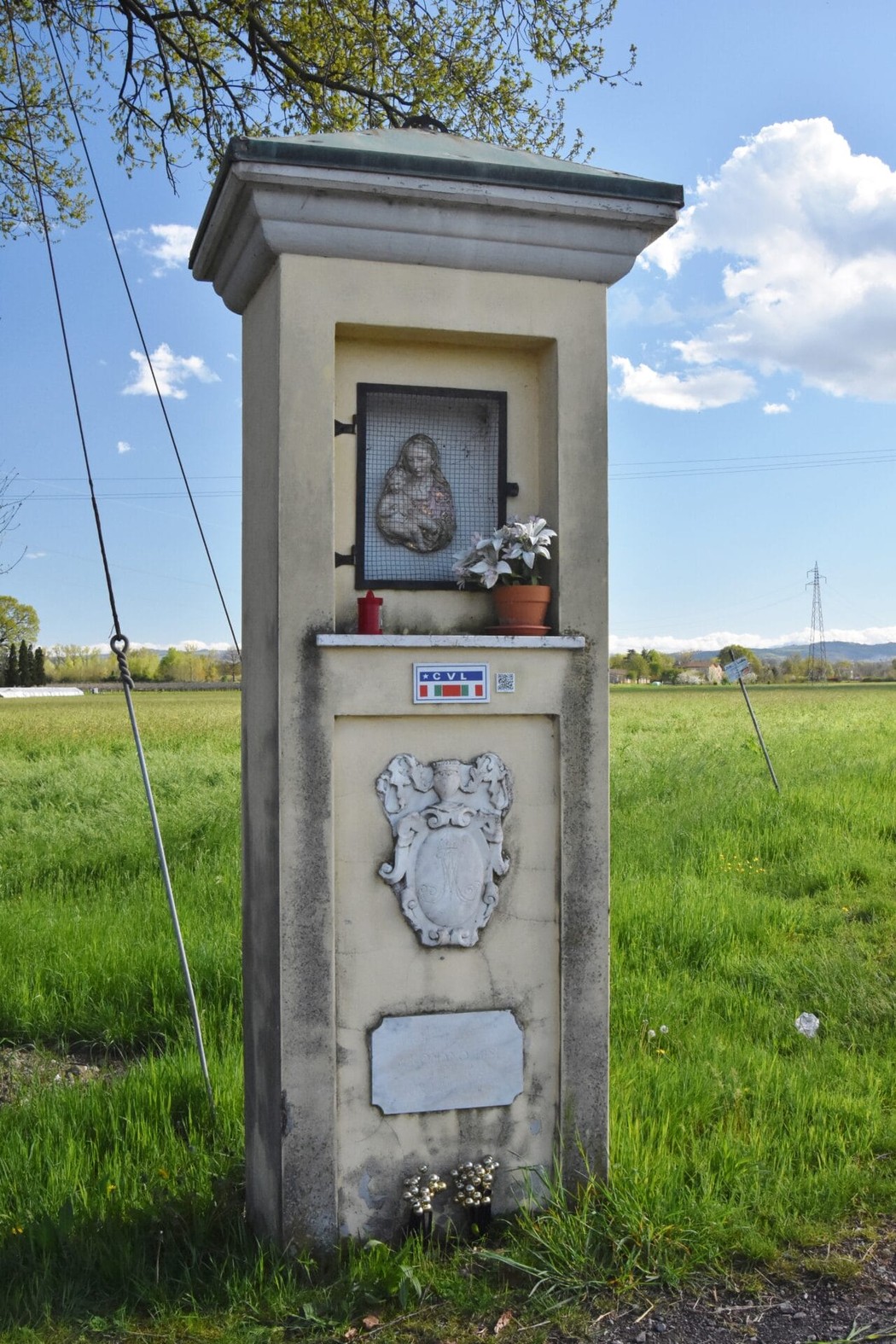 Tabernacolo con affresco e decorazioni, situato nei pressi di Bisi e Argiolas, circondato da un paesaggio verde.