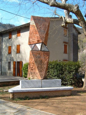 Monumento della piazza di Sant'Anna con sculture in rilievo e base in marmo, circondato da natura e edifici.