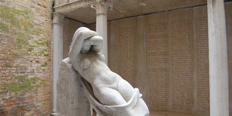 Scultura nel "Sacrario degli studenti universitari caduti", con colonne e iscrizioni commemorative sullo sfondo.