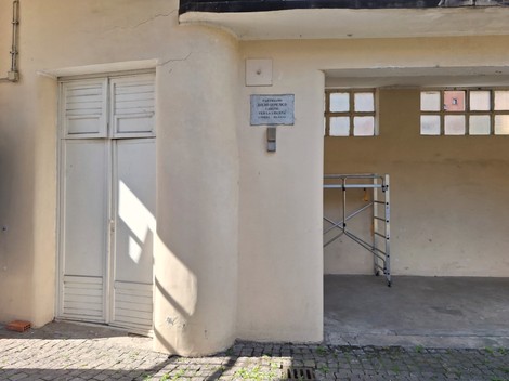Lapide commemorativa affissa su un muro vicino a un ingresso, con area di lavoro accessoria.