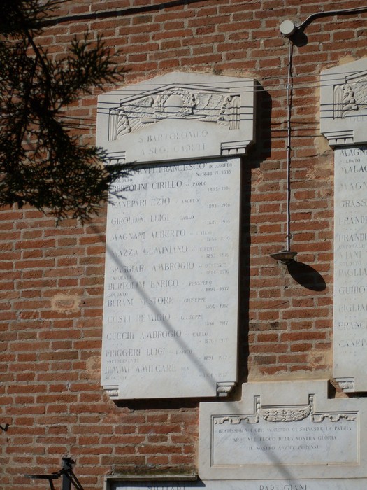 Lapide commemorativa ai caduti di San Bartolomeo, incisa su pietra e affissa a un muro in mattoni.