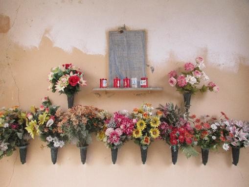 Lapide commemorativa decorata con fiori freschi e candele, in ricordo di Bonino e Coda.