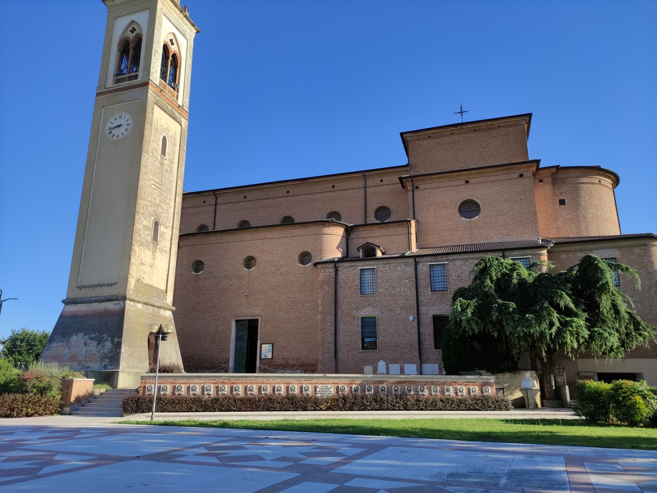Monumento commemorativo degli eventi tragici di Santa Giustina in Colle, con vista sulla chiesa e il campanile.