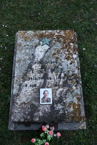 Tomba del "Sacrario dei partigiani pratesi" con pianta e foto commemorativa di un partigiano.