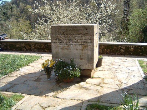 Monumento dedicato ai caduti nella piazza di Sant'Anna, circondato da fiori e natura.