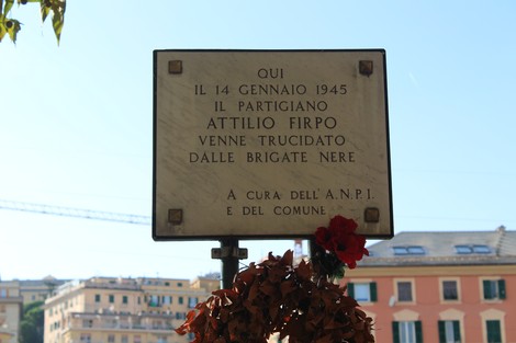 Lapide commemorativa dedicata al partigiano Attilio Firpo, situata in un contesto urbano.