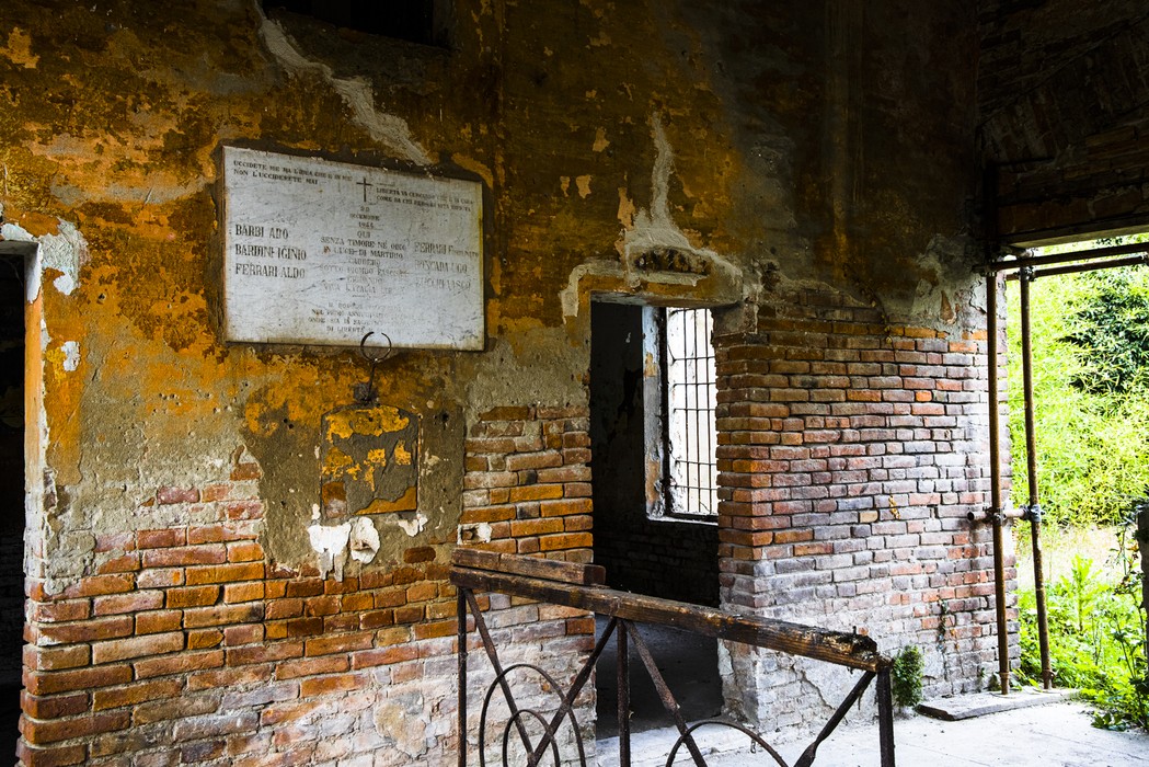 Interno del Poligono di tiro di Gonzaga, con pareti di mattoni e affreschi degradata.
