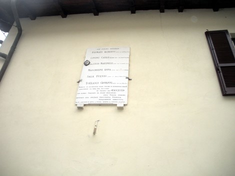 Lapide commemorativa con nomi di persone, installata su una parete esterna.