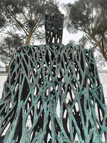 Scultura monumentale nel Cimitero militare italiano di Zehlendorf, con alberi sullo sfondo.