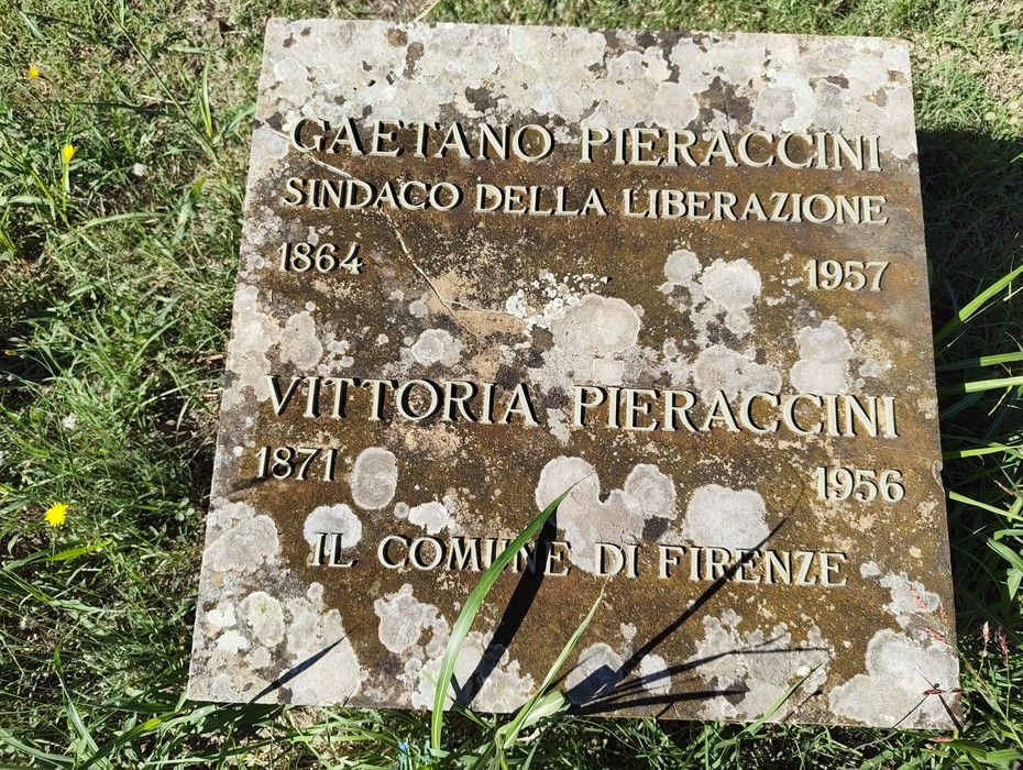 Lastra tombale in pietra su prato, con iscrizione incisa e macchie di licheni sulla superficie.