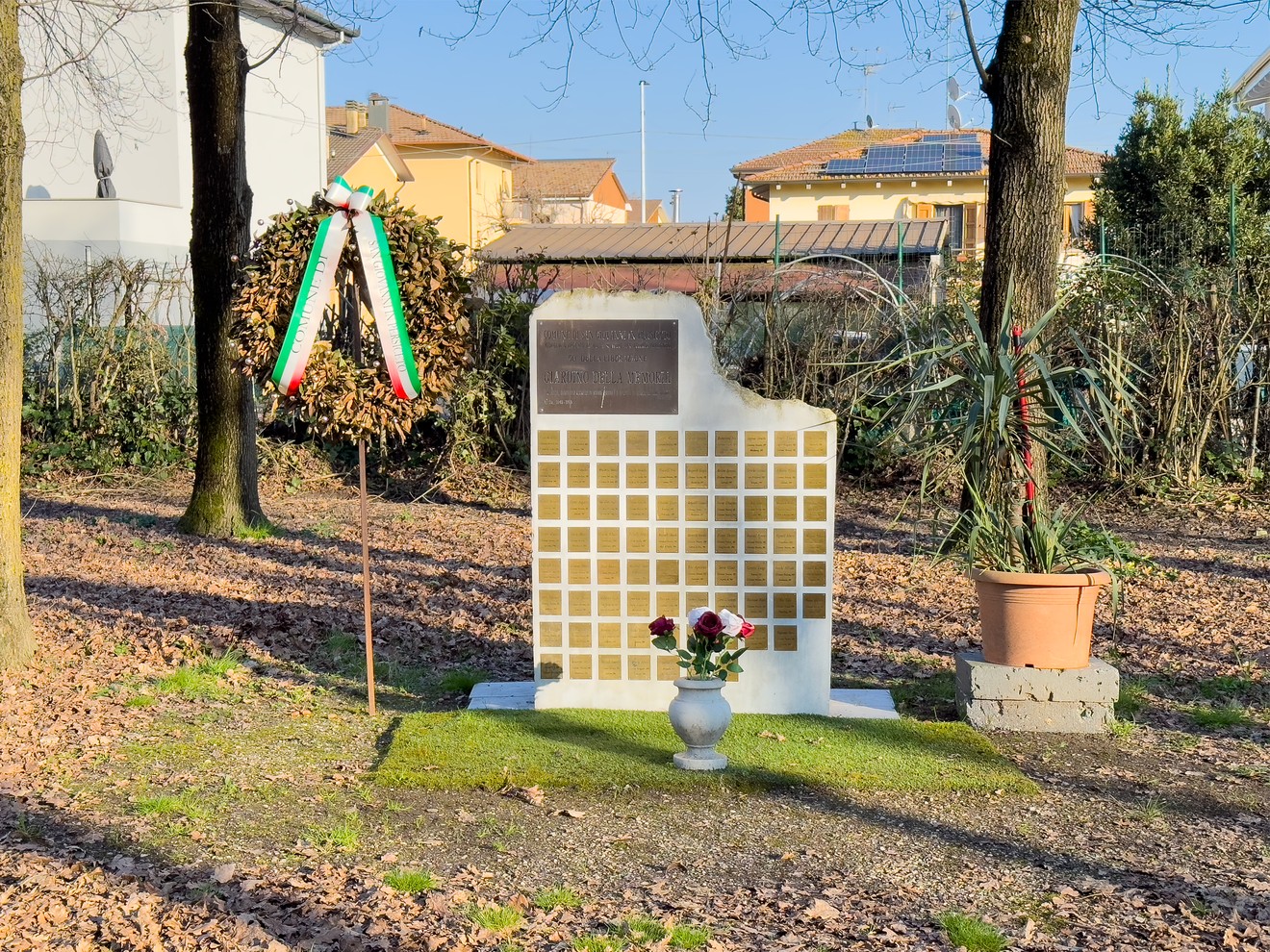 Il Giardino della Memoria con un monumento commemorativo e decorazioni floreali in un ambiente sereno.