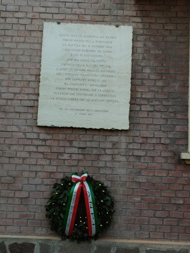 Lapide commemorativa della base partigiana, con corona d'alloro e tricolore italiano. Rappresenta la memoria storica.