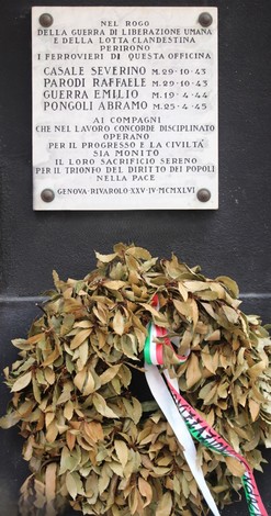 Lapide commemorativa dedicata ai ferrovieri caduti per la Libertà, adornata da un mazzo di foglie.