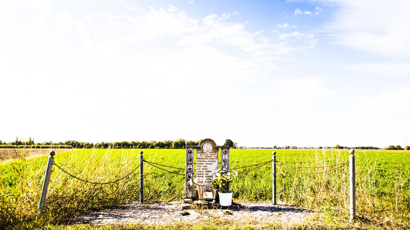 Monumento dedicato ai lavoratori uccisi, immerso in un paesaggio rurale aperto.