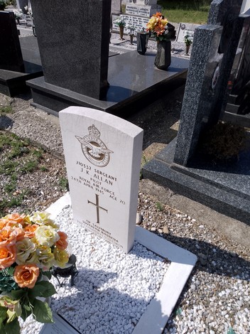 Tomba di Allan con lapide elegante e fiori decorativi in un cimitero ordinato.