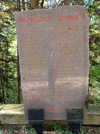 Memoriale dedicato ai caduti della Benedicta circondato da alberi, con una lapide commemorativa in pietra.