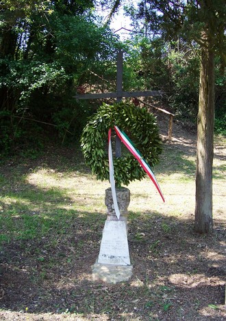 Cippo di Perelli con corona di alloro e nastri tricolori, simbolo di commemorazione e memoria.