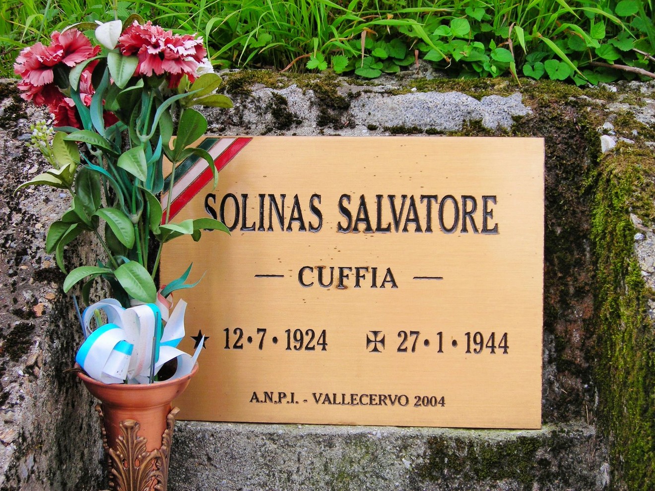Targa commemorativa dedicata a Salvatore Solinas, con fiori e simboli di onore e memoria.