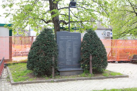 Cippo commemorativo dedicato ai partigiani del Pontevecchio, circondato da alberi e siepi, in un'area verde.