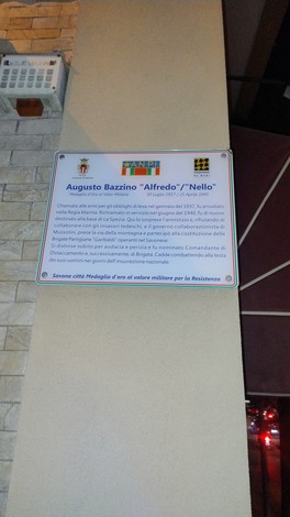 Targa commemorativa dedicata ad Augusto Bazzino, situata su un muro, con informazioni storiche e riconoscimenti.