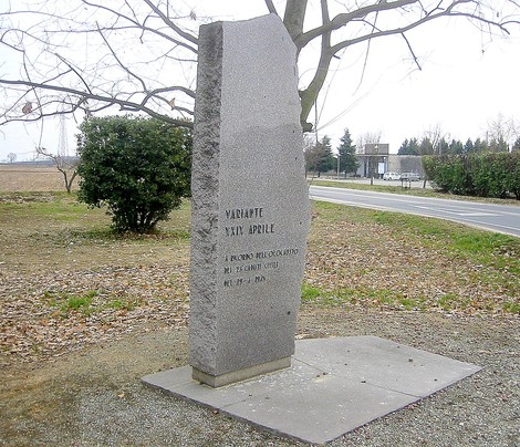 Stele commemorativa in pietra dedicata ai caduti del 29 aprile, situata in un'area rurale.